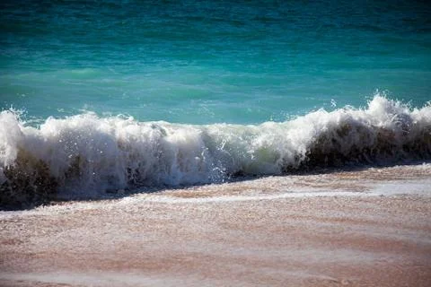 Surf breaking on the sandy beach Stock Photos