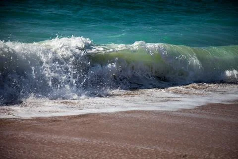 Surf breaking on the sandy beach Stock Photos