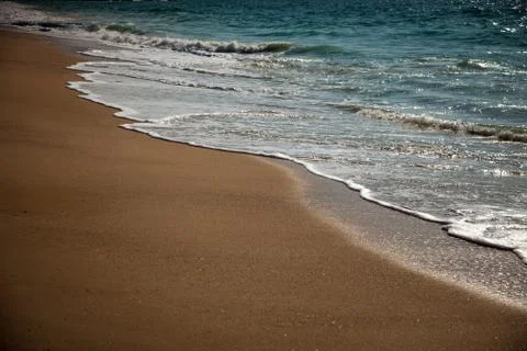 Surf breaking on the sandy beach Stock Photos