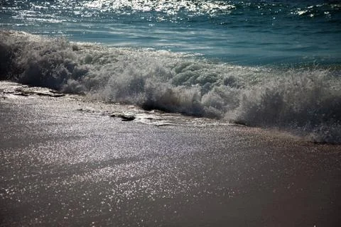 Surf breaking on the sandy beach Stock Photos