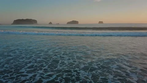 Surf breaks on a tropical beach with islands in the background 库存影片 148080348