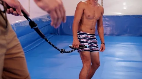 Surf instructor gives lesson to young guy on wave simulator indoors. Young Stock Footage 212363513