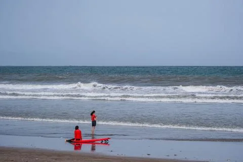 Surf Instructors with Red Board on an Overcast Beach Stock-Fotos