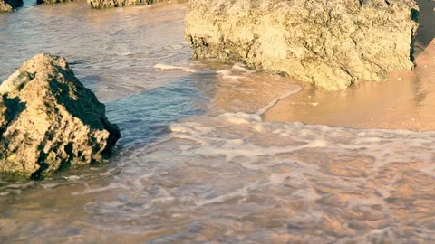 Surf lapping at rocks on a sandy beach Stock Footage 121458774