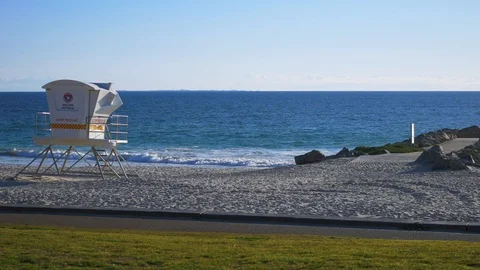 Surf life saving tower overlooking rocks at the beach at sunset Stock Footage 94268394