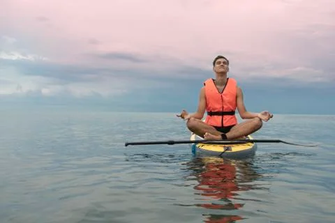Surf man in life jacket does yoga and meditation on a sup surfboard, Concept  Stock Photos