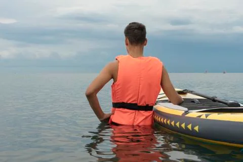 Surf man in life jacket is preparing to surfing. Young man with surfboard on  Stock Photos