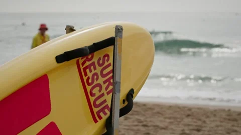 Surf rescue board secured on a beach rack with ocean waves in the background Stock Footage 337686135