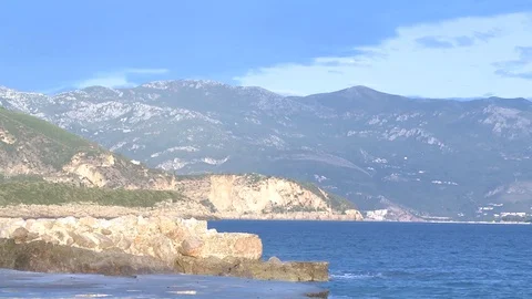 Surf on stone beach in front of mountains in summer 스톡 동영상 84316316