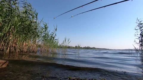 Surf wave on a small lake, foam, fishing rods and reeds. Stock Footage 138874622