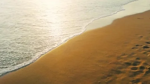 Surf waves on yellow sand at sunset Video stock 168925790
