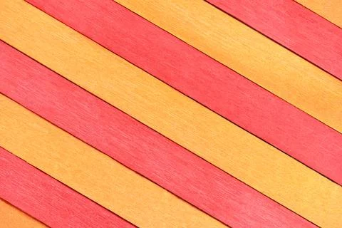 The surface of alternating red and orange wooden planks arranged diagonally. Photos