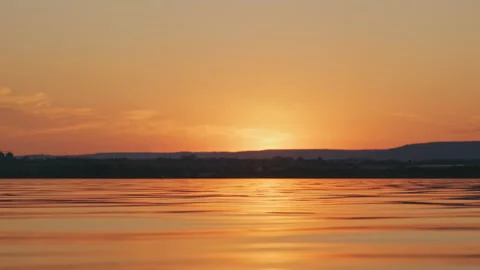 Surface of beautiful lake with small waves of sunrise on of mountain peaks Stock Footage 141423979