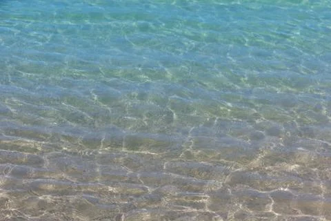 Surface of blue ocean or clear water reflections on sandy beach bottom Stock Photos