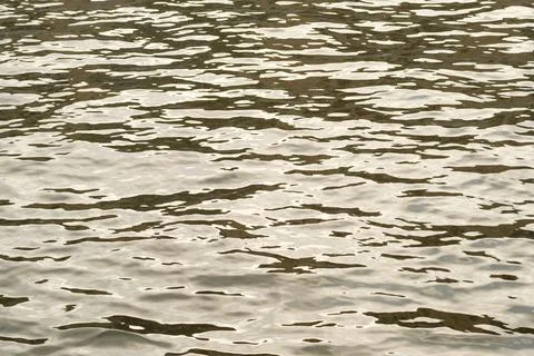 Surface of calm water reflecting light with gentle ripples and variations in Stock Photos