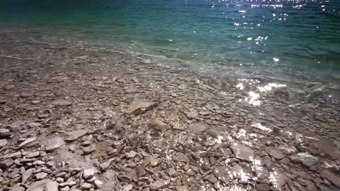 The surface of the clear water of a mountain lake reflects the sun's rays 動画素材 165025586