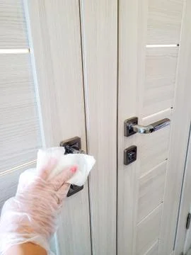 Surface of common use door handles are wiped with a disinfecting cloth to Stock Photos
