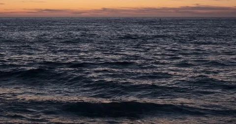 Surface of the dark ocean at dusk, with slow rolling waves and red sky Stock Footage 115758037