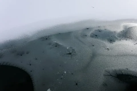 Surface of the deeep black water is covered by ice. lake, pond and water rese Stock Photos