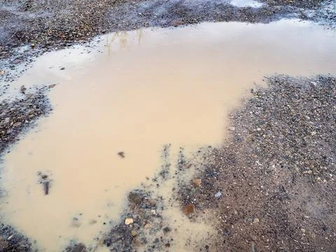 Surface of dirty rain puddle on gravel road Stock Photos