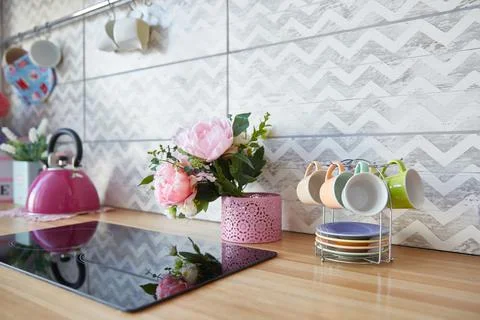 The surface of the kitchen set with a black hob. Flowers and cups on the kitchen Fotos Stock