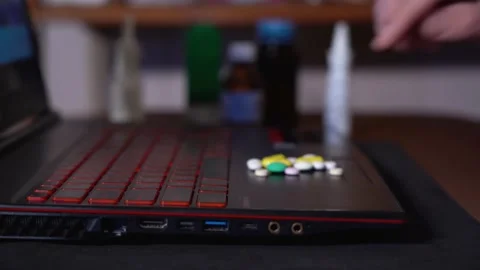 On the surface of the laptop are colored pill that I take in hand. Stock Footage 130199092