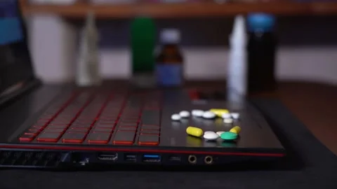 On the surface of the laptop, colored pills that I take in hand. Stock Footage 130199132
