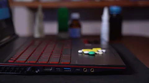 On the surface of the laptop move colored tablets in a pile. blurred background Stock Footage 128841094
