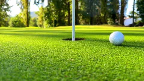 Surface Level on a Golf Ball Rolling in the Hole in a Sunny Day in Switzerland Stock Footage 252050855