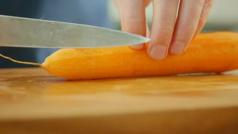 Surface Level Shot Of Man's Hands Cutting Fresh Carrot Stock Footage 86069075