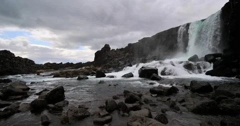 Surface Level View of Kirkjufellsfoss Waterfall Flowing Over Volcanic Rocks in Stock Footage 342291333