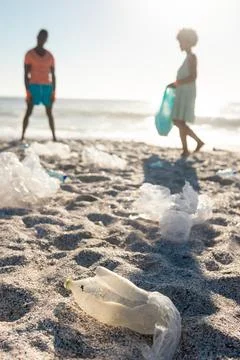 Surface level view of plastic garbage scattered against african american couple Stock Photos