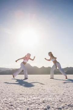 Surface level view of two women performing capoeira on Bonneville Salt Flats, Stock Photos