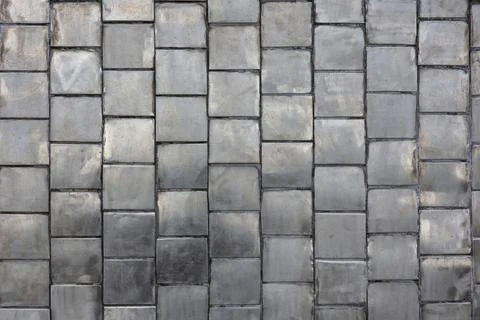 The surface is paved with old square metal tiles. Weathered stainless steel t Stock Photos