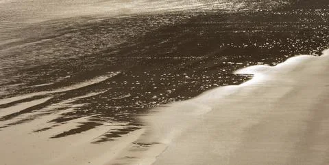Surface of a sandy beach in Cyprus at evening light. Calm gentle surf with so Stock Photos