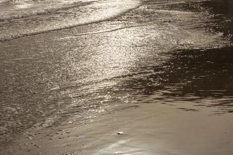 Surface of a sandy beach in Cyprus at evening light. Calm gentle surf with so Stock Photos
