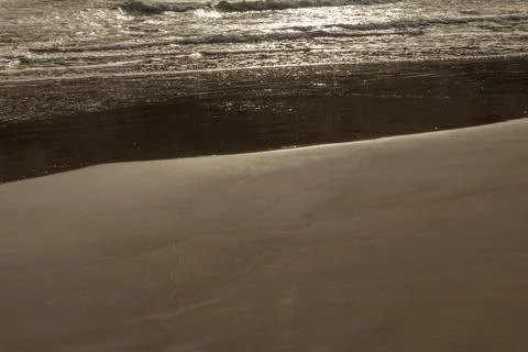 Surface of a sandy beach in Cyprus at evening light. Calm gentle surf with so Stock Photos