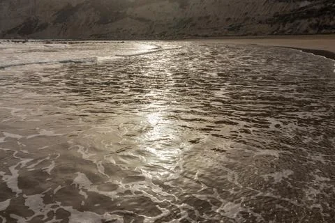 Surface of a sandy beach in Cyprus at evening light. Calm gentle surf with so Stock Photos