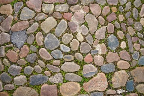The surface of the sidewalk lined with untreated cobblestone. View from above Stock Photos
