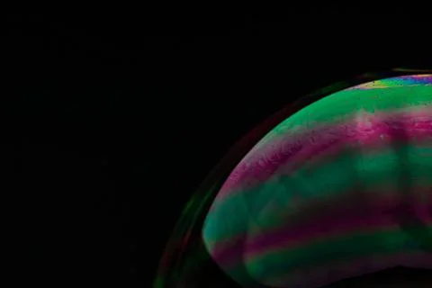 Surface of a soap bubble with colorful abstract patterns on a dark background Stock Photos