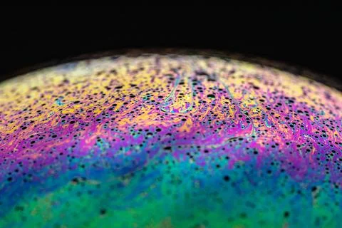 Surface of a soap bubble with colorful patterns on a dark background Stock Photos