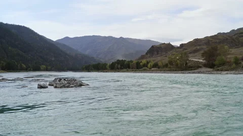 Surface of stormy river with rocky rapids, hills and mountains at horizon Stock Footage 194498886