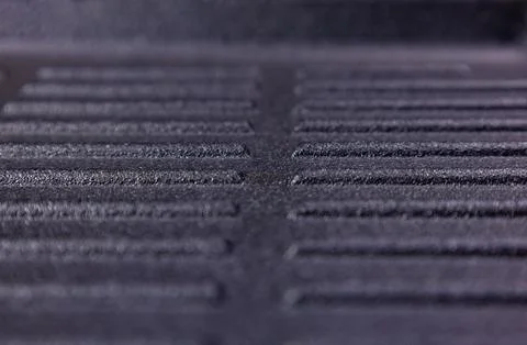 Surface texture of a black metal object in close-up view with grid pattern and Stockfoto's