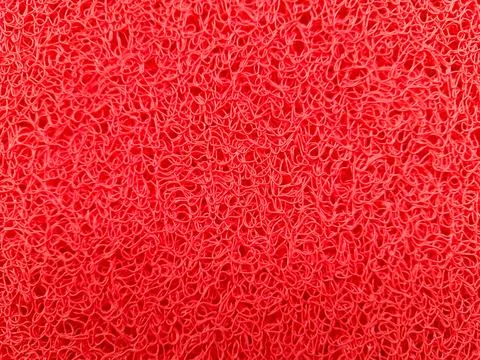 The surface texture of the red PVC doormat has a tangled and messy pattern. Stock Photos