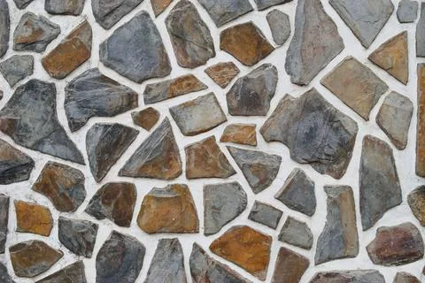 Surface texture of a wall built by irregularly shaped stone pieces Stock Photos