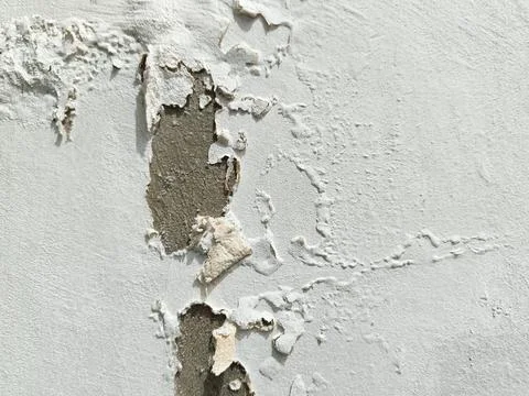 The surface texture of the wall is white with peeling paint. Stock Photos