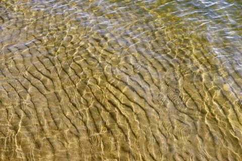 The surface of the water is pierced by the suns rays, the sandy bottom is vis Stock Photos