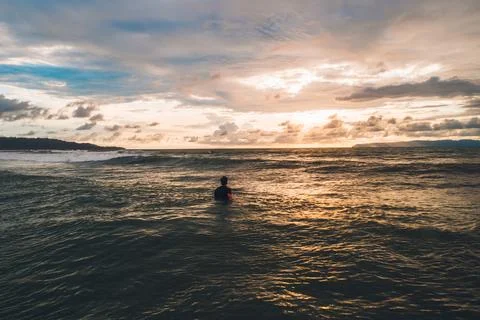 Surfer awaiting waves at sunset Stock Photos