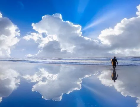 Surfer on beach with beautiful clouds reflections Stock Photos