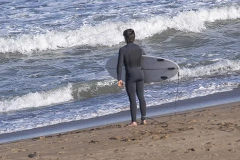 Surfer on the beach , looking at the waves , preparing to enter into the water Stock Photos